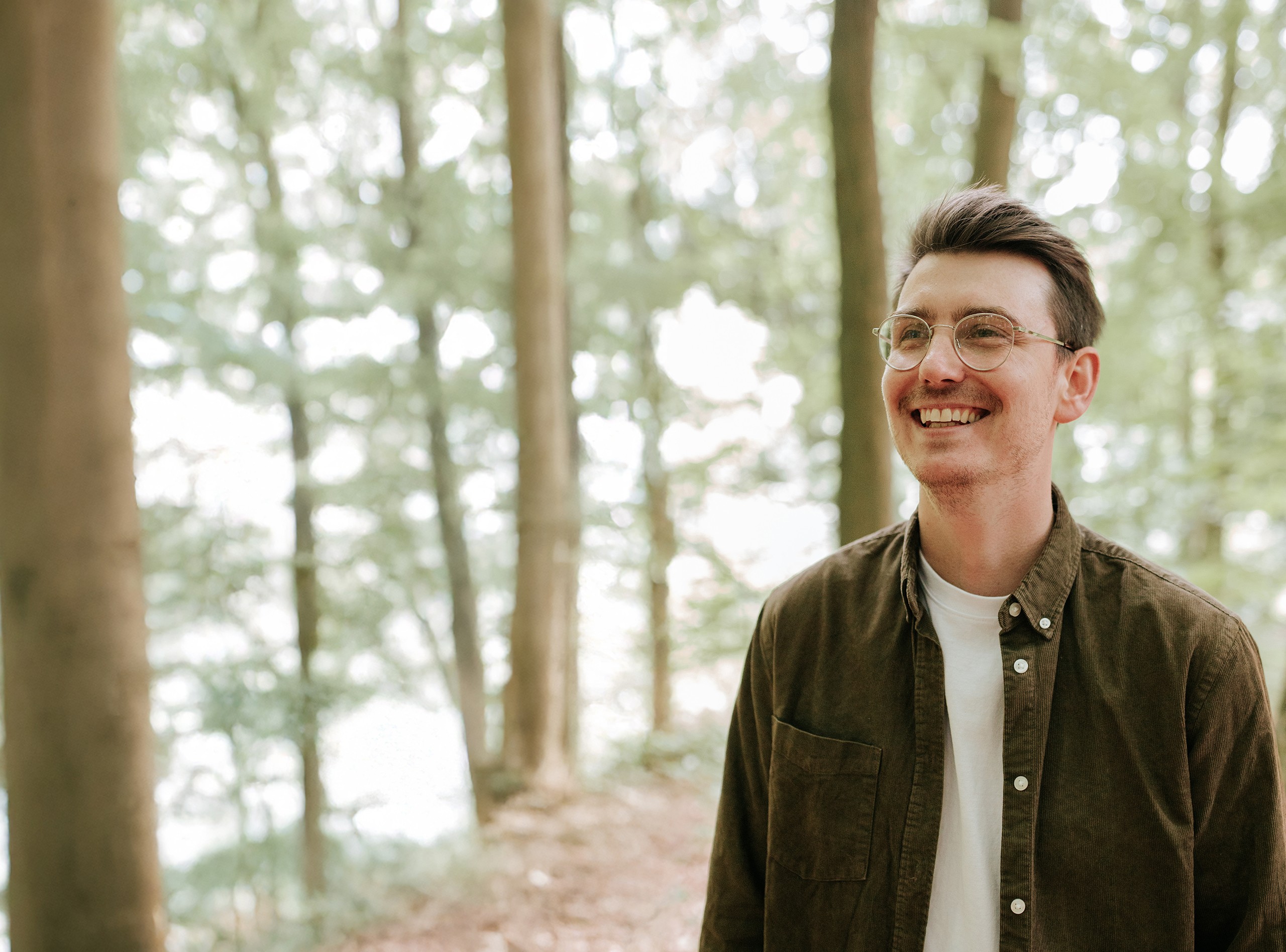 man smiling and looking away in sunny forest