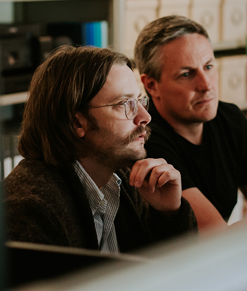 two guys working together looking at screen