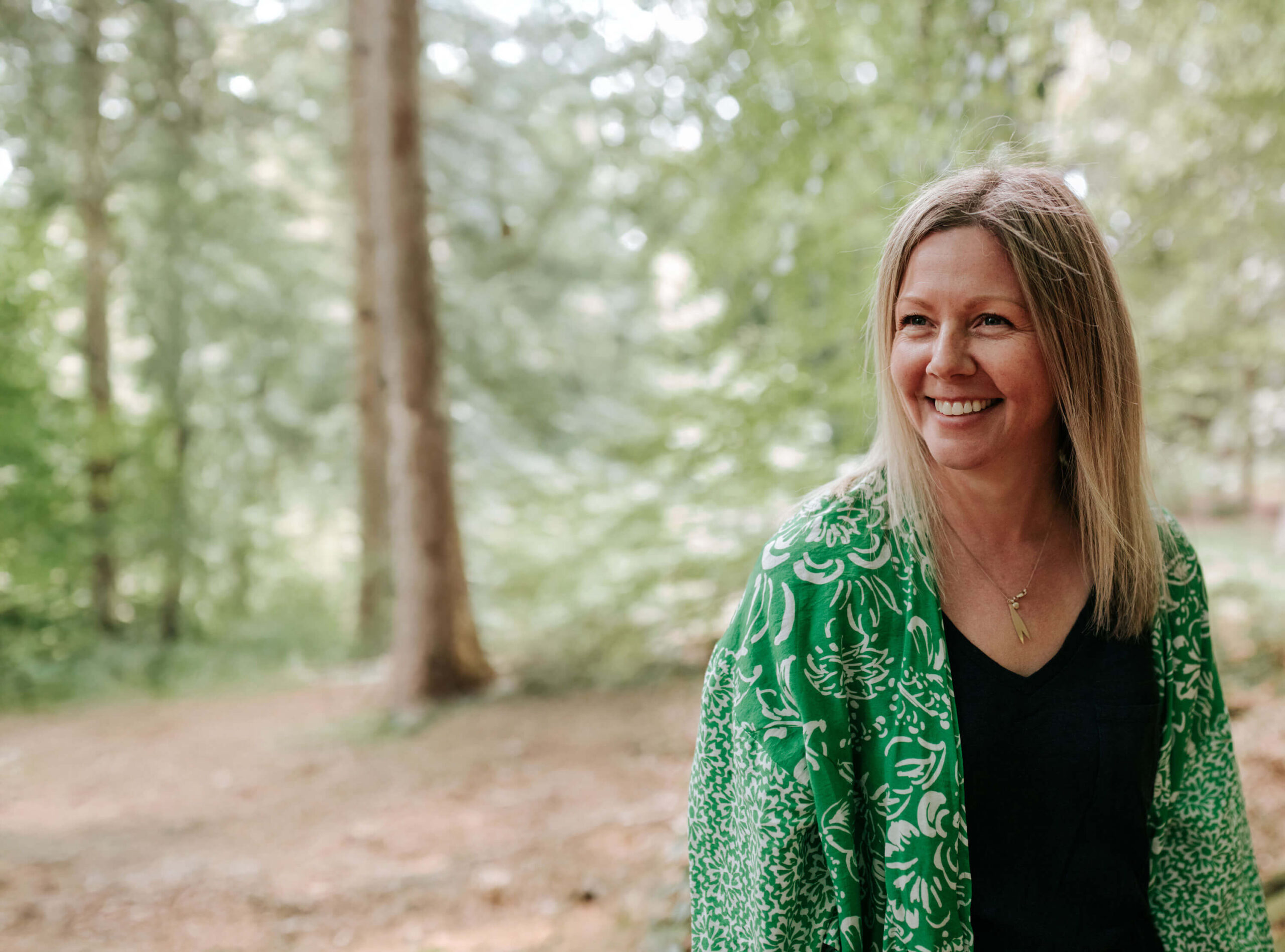 blonde woman smiling in woods photoshoot